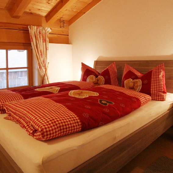 De boerderijwoning Farnreit verwelkomt je in Brixen im Thale met een mooi opgemaakt bed AT-6364-111_Farnreit_kussens_Oostenrijk_Belvilla vakantiehuizen